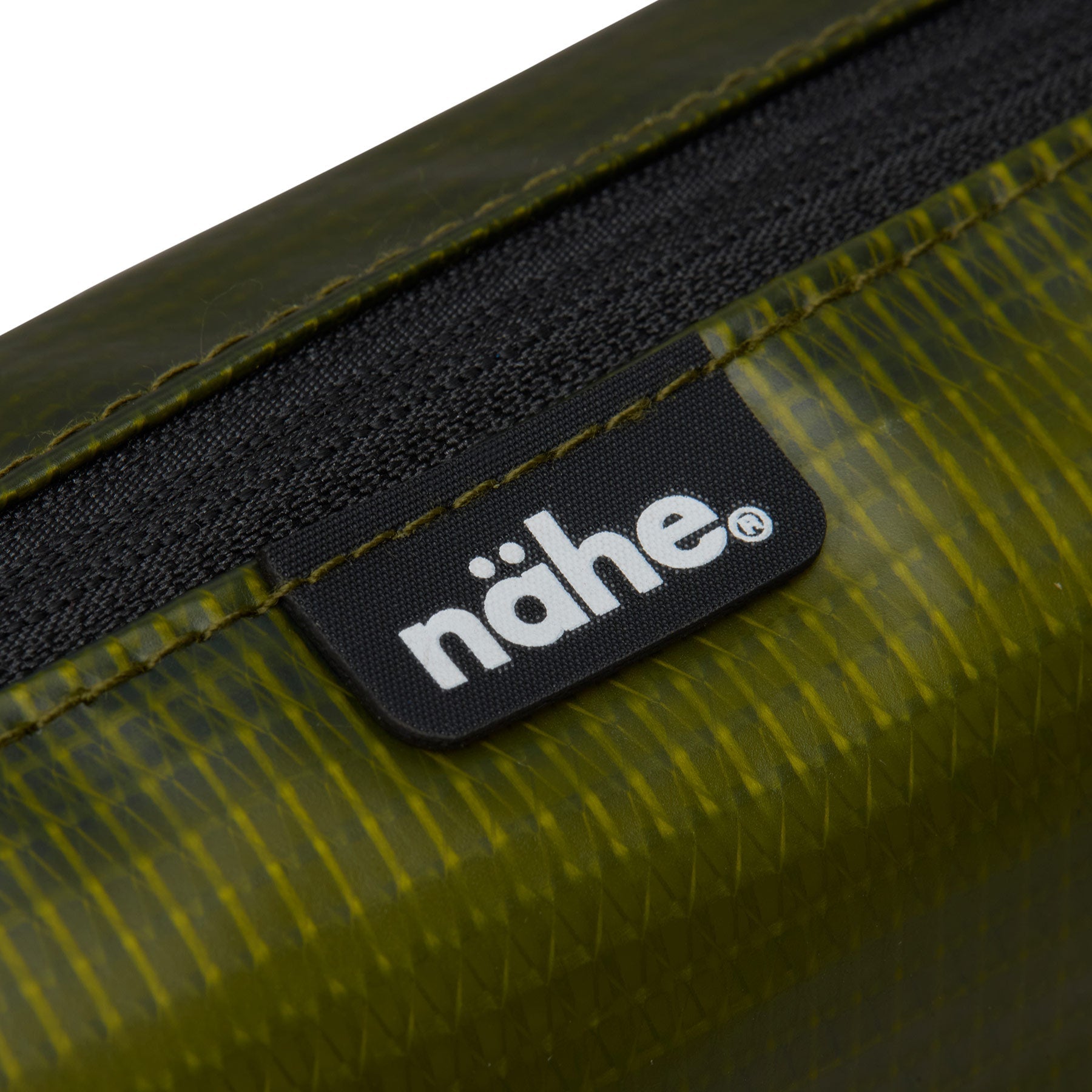Close-up of the Nähe logo tag on the Green grid-textured pouch, beside its black zipper trim.